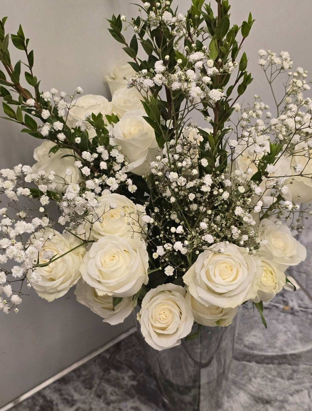 Dozen long stem white roses in tall glass vase