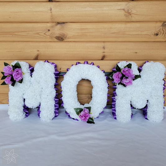 Floral arrangement spelling 'MOM' against a wooden background
